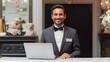 © Johannes - friendly hotel manager with warm welcoming smile standing behind his computer at front desk of luxury hotel