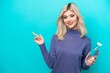 © luismolinero - Young Russian woman with a bottle of water isolated on blue background pointing finger to the side