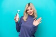 © luismolinero - Young Russian woman with a bottle of water isolated on blue background saluting with hand with happy expression
