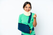 © luismolinero - Young hispanic woman wearing a neck brace and sling isolated on white background making money gesture