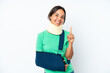 © luismolinero - Young hispanic woman wearing a neck brace and sling isolated on white background showing and lifting a finger