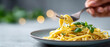 © Anastasiya Marchenko - Close-up of fork twirling creamy pasta with fresh basil leaves on a plate with blurred background