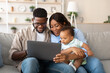 © Prostock-studio - Happy parents share a funny educational video on a laptop with their young son while relaxing on the sofa at home. The family is clearly excited and engaged in this joyful moment.