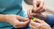 © gle - Woman healthcare worker helping senior woman string beads. Fine motor skill rehabilitation and occupational therapy for elderly patient.
