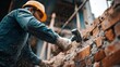 © Igor - Demolition Work: Worker Striking Brick Wall with a Sledgehammer