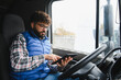 © Serhii - Truck driver using digital tablet inside vehicle cabin