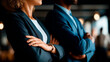 © Kateryna - Two confident business partners standing back to back with crossed arms faceless man and woman defocused professional background partnership equality success collaborative duo