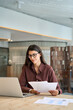 © Stock 4 You - Concentrated latin business woman saleswoman working on laptop computer reading financial bank tax document in office. Young manager businesswoman specialist doing bill paperwork using pc. Vertical