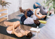 © JackF - Young woman practicing yoga with multinational group of people in modern studio, performing Pavana Muktasana to stretch and strengthen back and abdominal muscles