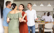 © JackF - Multiethnic women and men friends hugging when meeting party in kitchen at home
