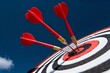 © NASSRI - Closeup red dart arrow hitting bullseye target center on dark blue background, business strategy success concept with accuracy, achievement, competition, score, marketing goal precision