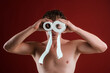 © Volodymyr - A funny man uses toilet paper rolls as goggles. Humorous portrait with a shocked crazy expression with toilet paper. Comical lifestyle scene with toilet paper. Restroom concept.