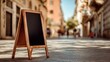 © hao - A blank sandwich board stands on a cobblestone street, blurred buildings in the background. High quality