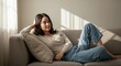 © CrazyJuke - Serene Solitude: A woman relaxes on the sofa, a picture of tranquility, the gentle sunlight illuminating the space. A moment of peaceful reflection and contentment.