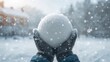 © The 2R Artificiality - Close-up of a large snowball held in hands, winter activity emphasizing snow precipitation, Winter Fun Day
