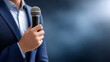 © Tetyana - Speaker holding a microphone during a public speaking event, conference presentation, corporate meeting, or live interview with ample copy space for advertising and communication with copy space