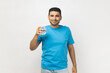 © khosrork - Optimistic satisfied man standing holding glass of water, looking at camera with positive emotions.