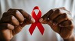 © Arifkki - African American hands tenderly holding red ribbon for AIDS awareness symbolizing hope, solidarity, and compassion during World AIDS Day campaign