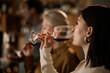 © Seventyfour - Young adult Caucasian woman tasting red wine in foreground, middle aged Caucasian woman and Black man sampling wine in background, people participating in wine tasting event