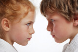 Close-Up Staredown of Two Children in Martial Arts Gi Facing Off — Intense Profile Portrait of Boy and Girl in Karate Showing Focused Determination