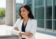 © Vasiliy - Confident smiling businesswoman standing outdoors. Portrait of a successful female professional in a modern corporate setting. Young executive looking away with confidence
