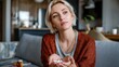 © Bargais - A woman sitting on the couch and holding pills.