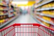 © Space Priest - Shopping cart in aisle of colorful grocery store with blurred shelves, defocused backdrop, copy space for text