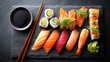 © backup_studio - Fresh sushi set with different types of rolls, nigiri, and maki on a slate plate, served with soy sauce, wasabi, and ginger for a delicious meal.
