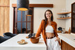 © SHOTPRIME STUDIO - Young woman cooking in a stylish kitchen, wearing a casual outfit with a smile, representing healthy eating and modern lifestyle
