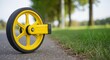 © kodidesign - Yellow measuring wheel on asphalt road. Surveyor tool for measuring distance outdoors. Construction and engineering equipment with copy space