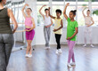 © JackF - Teenage African American girl in vibrant workout clothes practicing basic ballet moves with other beginners at group class led by female choreographer..