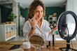 © Miljan Živković - Woman recording makeup tutorial using smart phone and ring light