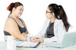 © Creativa Images - Doctor taking blood pressure while discussing health risks with obese patient