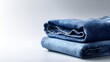 © irawan - Stack of neatly folded blue denim trousers resting on a light surface with ample copy space