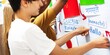 © Rawpixel.com - Students placing multilingual greeting cards on a board. Diverse group engaging with language learning. Multilingual interaction with greetings. Students learning in classroom with nation flags.