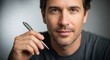 © Tristin - Confident man holding a pen with a subtle smile and focused gaze