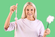 © Pixel-Shot - Mature woman with mouth gag and feather stick from sex shop on green background