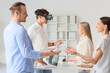 © Pixel-Shot - Young man using VR glasses with his colleagues in office