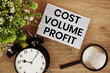 © may1985 - Cost Volume Profit text in lightbox with magnifying glass and alarm clock flat lay on wooden background