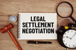 © may1985 - Legal Settlement Negotiation message written on notepad with alarm clock, wood gavel and magnifying glass flat lay on wooden background