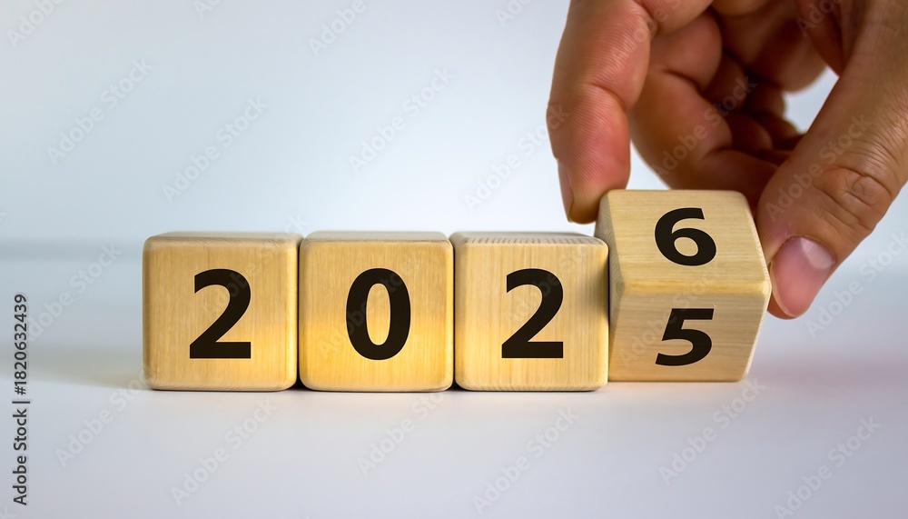 Hand flipping wooden blocks from 2025 to 2026 representing the ...