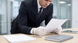© Đào Tuấn Anh - Focused Businessman In Suit Wearing Protective Gloves Reading Document Evidence At Office Desk