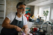 © Cavan Images - Man preparing a meal in a bright kitchen while chopping vegetables