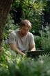 © Iryna - Young caucasian male using laptop outdoors in lush garden setting