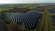 © AmazingAerialAgency - Aerial view of solar panels basking in the soft sunlight against the backdrop of green fields and distant structures, Newmarket, England, United Kingdom.