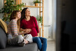 © NDABCREATIVITY - Happy pregnant mother and teen daughter having pleasant conversation, laughing, chatting at home