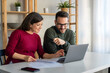 © NDABCREATIVITY - Happy businesspeople laughing while collaborating on a new project in an office.