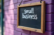 © miss irine - Small business sign on purple brick wall with chalk writing. Support local shops and community businesses. Ideal for marketing or retail concepts. Buy local movement.