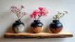 © tauviqemya - Three decorative ceramic vases, each holding a different type of flower, are arranged on a rustic wooden shelf against a plain background. The lighting is soft