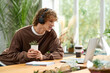 © Bliss - Young creative man enjoys work and plants in bright indoor workspace during daytime
